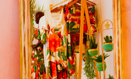 Rack of vibrant clothing with potted plants