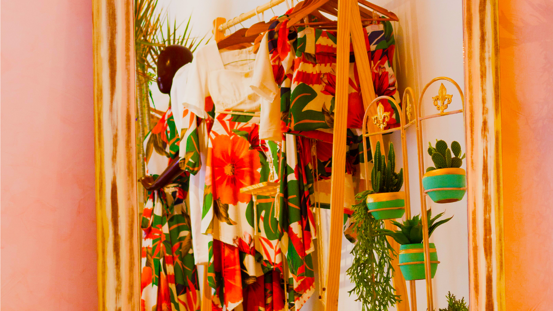 Rack of vibrant clothing with potted plants