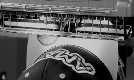 Black and White Image of Melco Embroidery Machine embroidering onto a cap