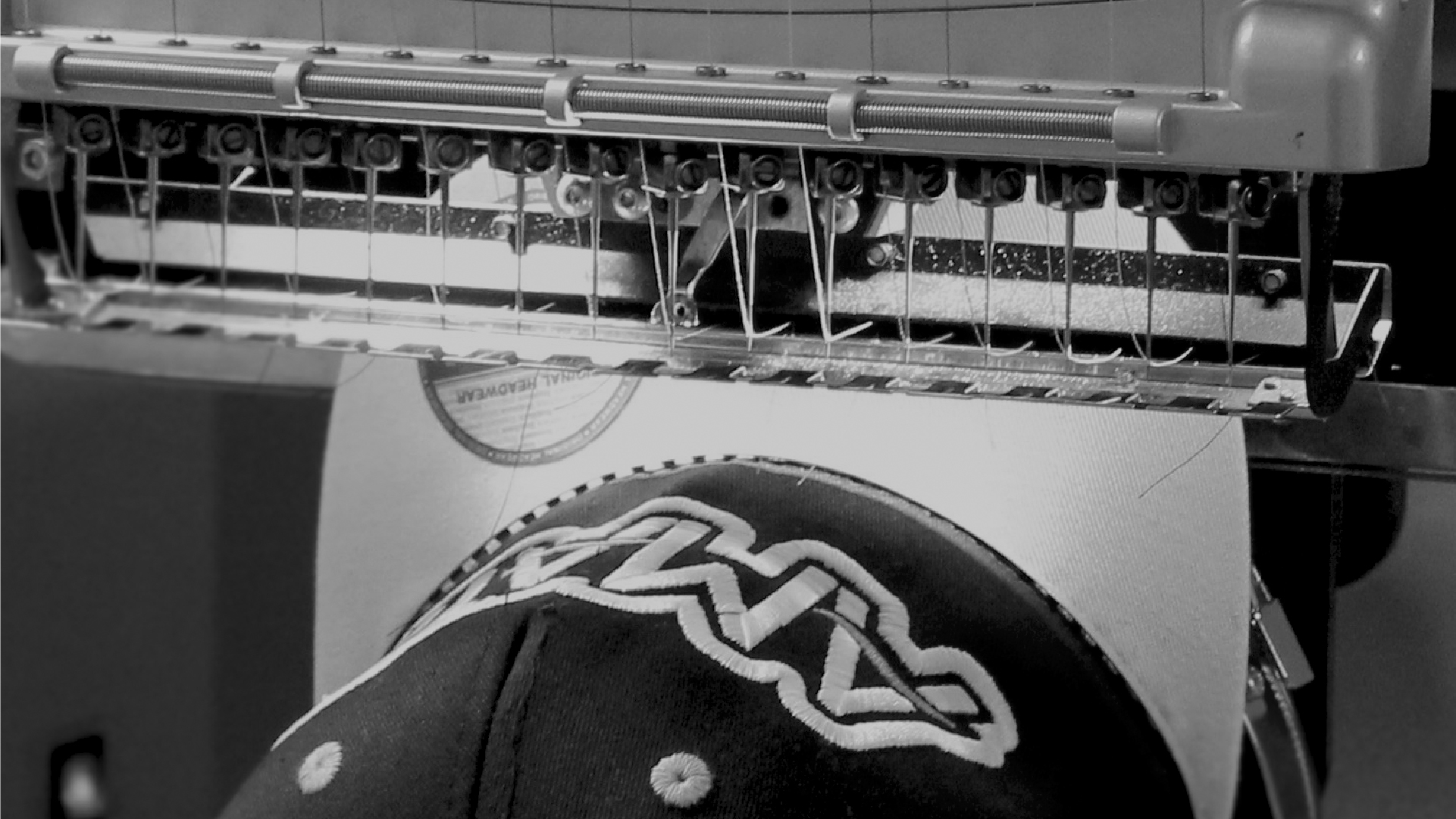 Black and White Image of Melco Embroidery Machine embroidering onto a cap