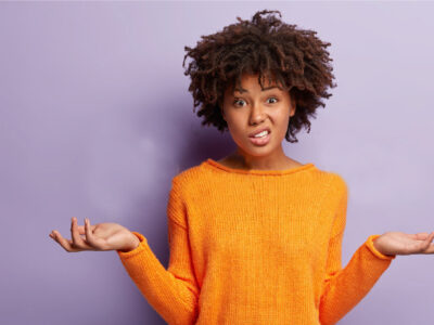 Black woman with orange jumper looking confused