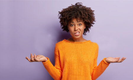 Black woman with orange jumper looking confused