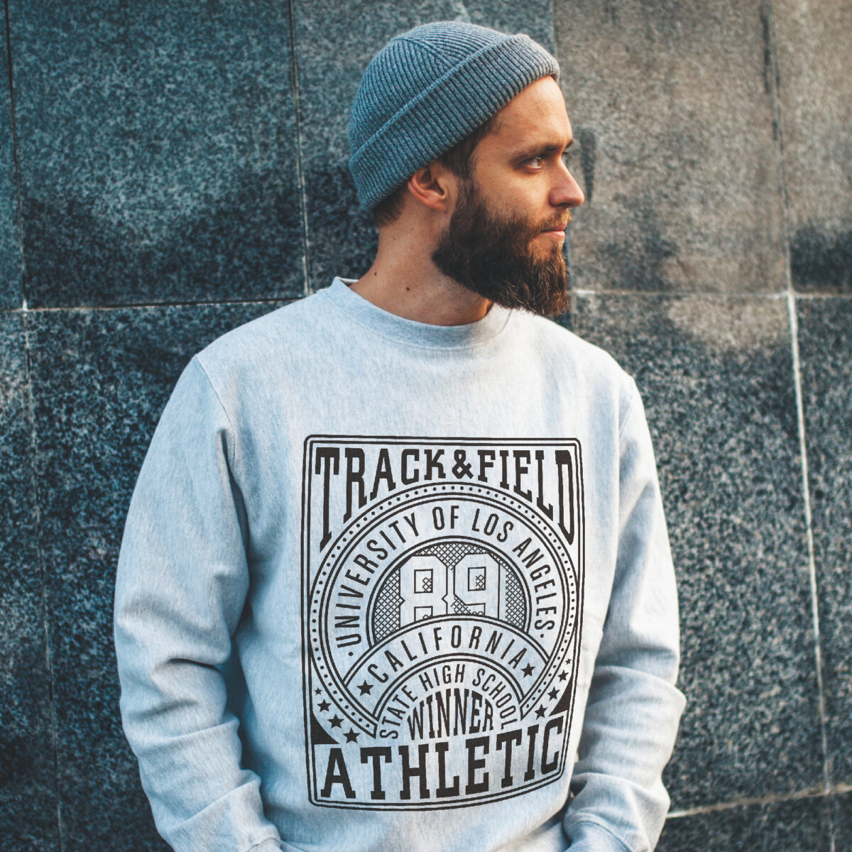 Man outside in beanie with a grey sweatshirt with a track and field print made with Forever Classic and Universal Paper