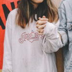 Woman holding persons hand in white Hoody