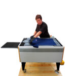 Man placing dark blue garment onto Chiossi Speedy T Folding Machine